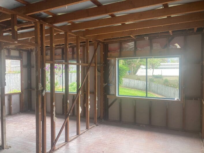 Room stripped to the timber frame after asbestos wall linings were removed, windows still in place